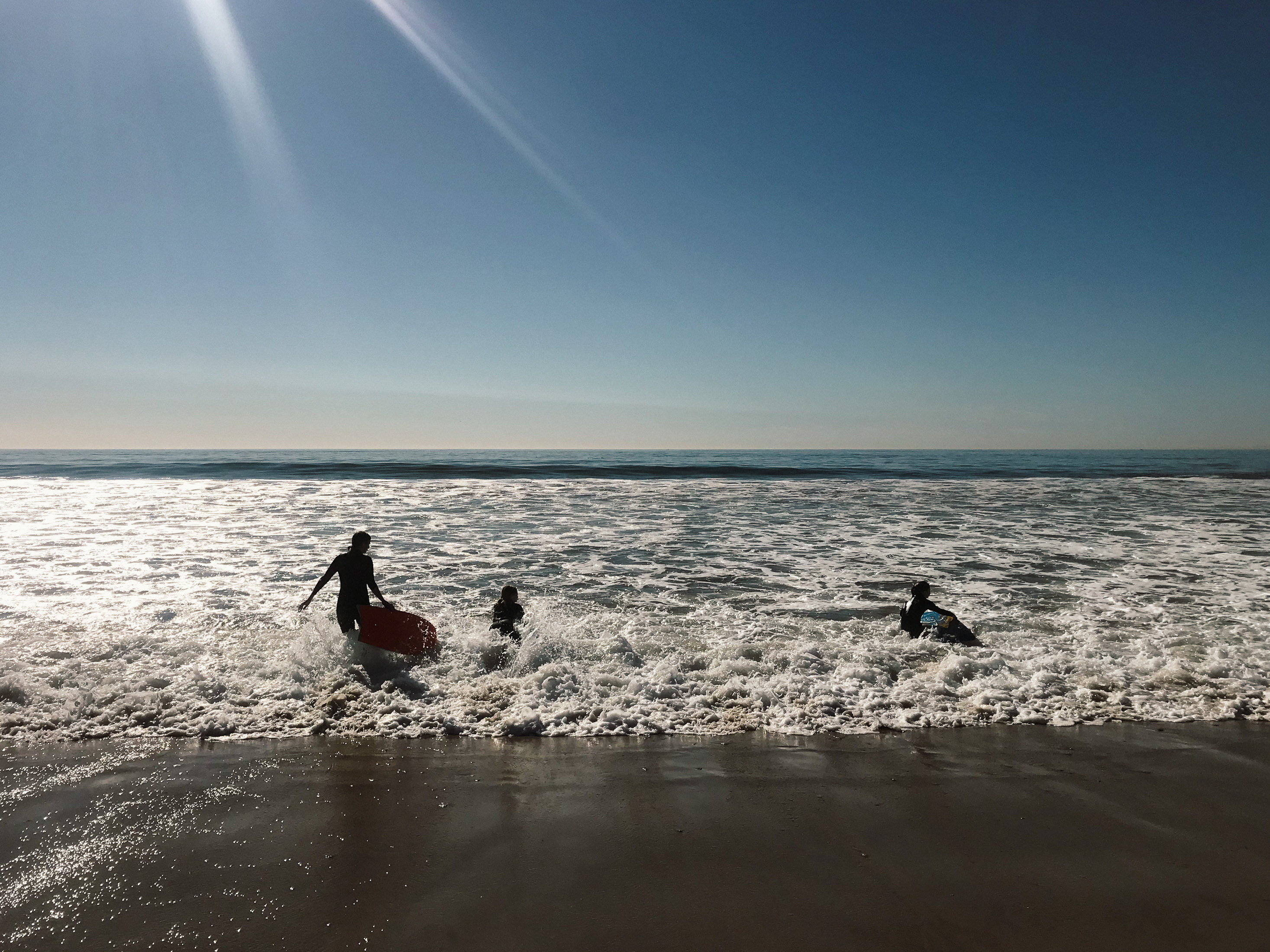 Young Family Playing in Waves At Beach in California