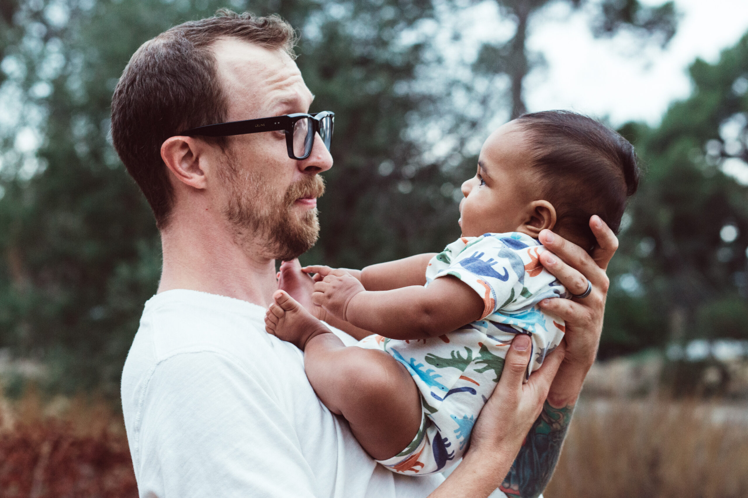 Dad Holding Baby and Smirking Outside in California Studio Sido