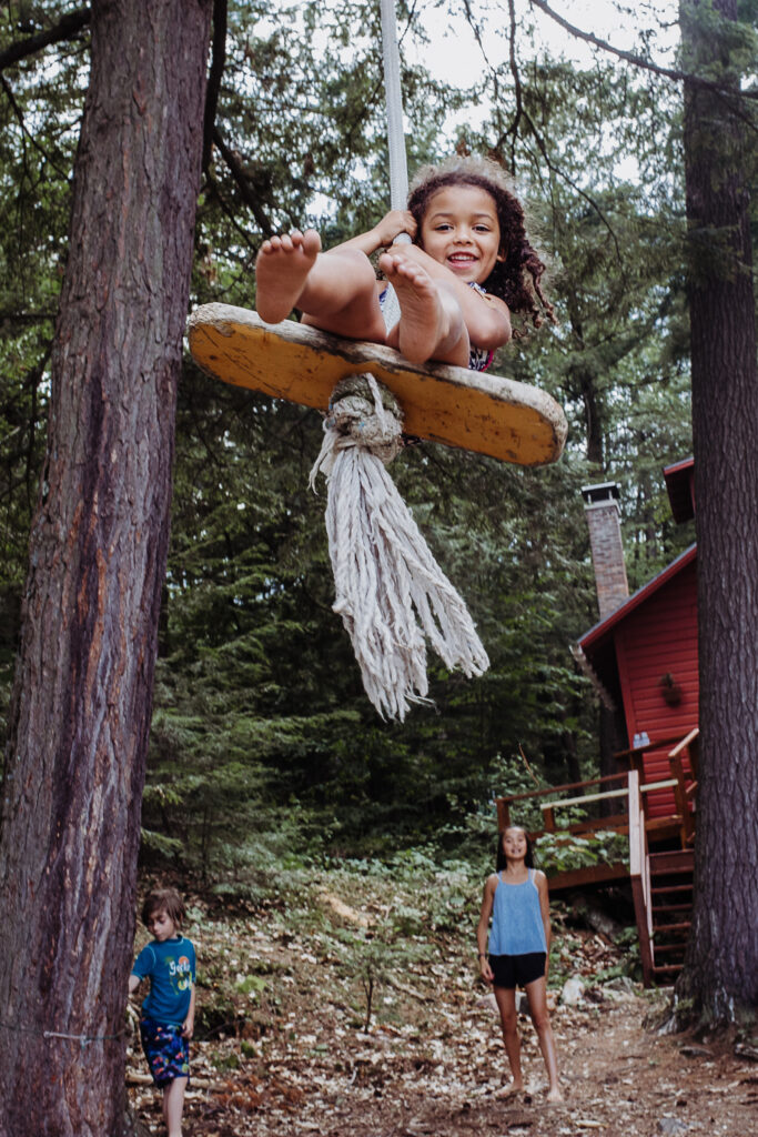 Young Child Swinging on Rope Swing in Woods