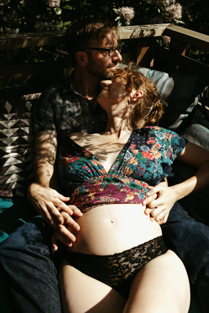 A pregnant woman lies against her partner