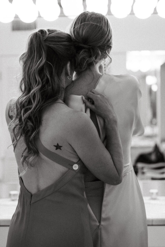 Bride and bridesmaid take a moment as the bride puts on her dress in Palm Springs, CA