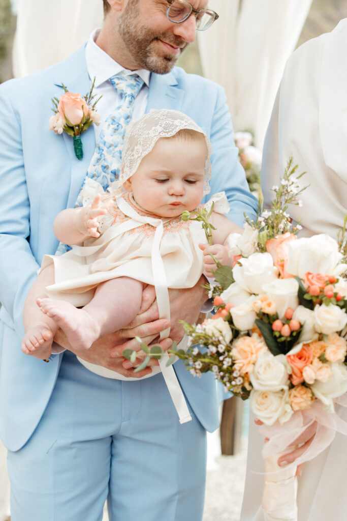 The groom holds his baby at his wedding in Palm Springs, CA