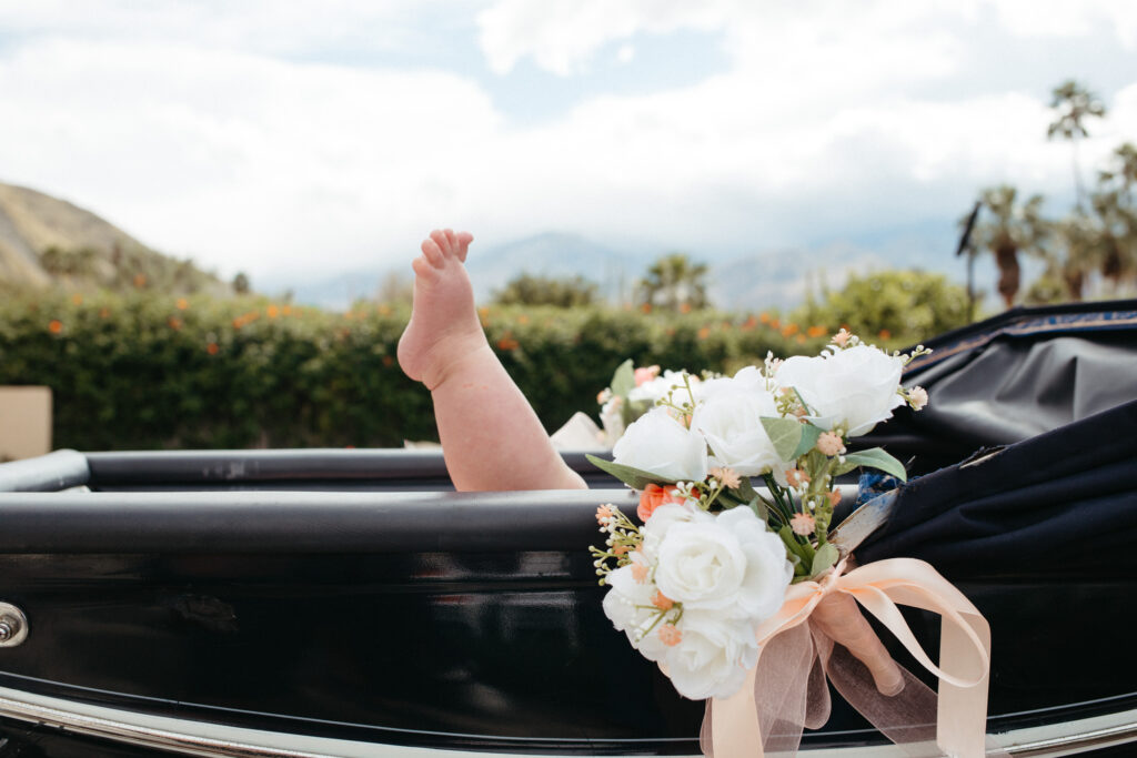 A baby's leg can be seen poking out of her baby carriage at a wedding in Palm Springs, CA