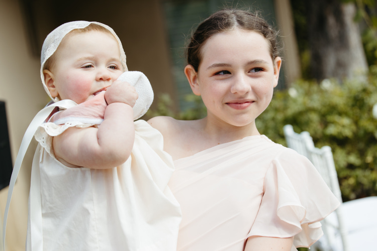 Young girl holding baby at wedding in Palm Springs, California