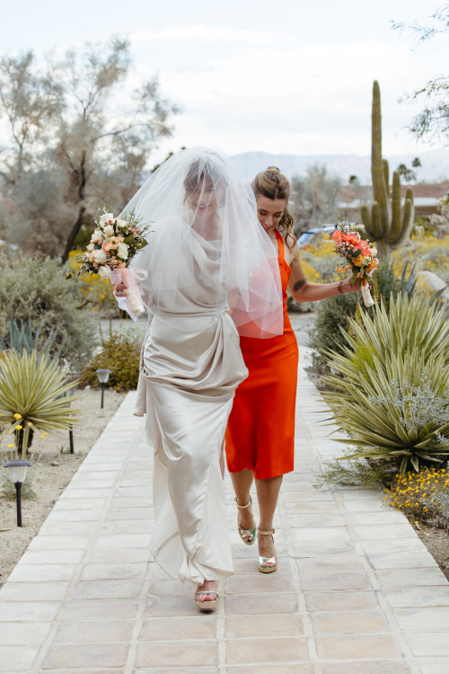 Bride walking with veil down with bridesmaid at a Palm Springs Wedding