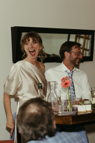 Bride laughing with groom in background